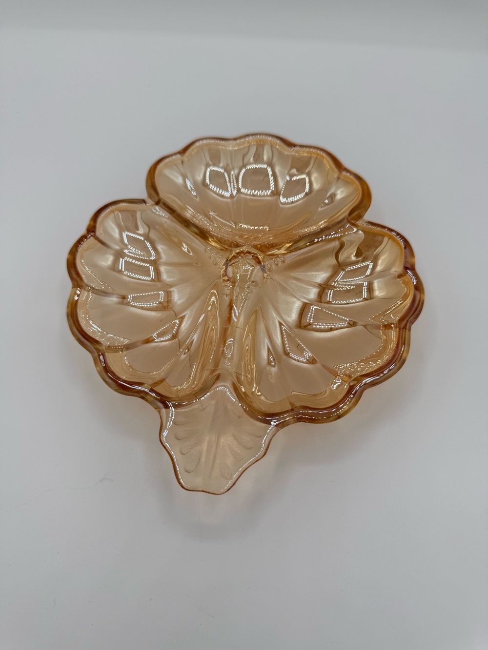 Amber marigold carnival glass three-lobed clover dish with molded patterns.